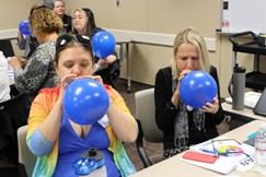 students in a classroom blowing up blue balloons