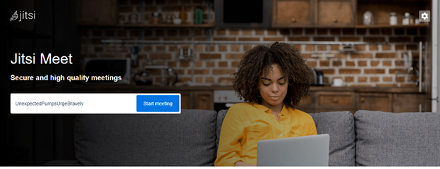 Home page of Jitsi.meet. Young woman working on her laptop at home, kitchen in the background.