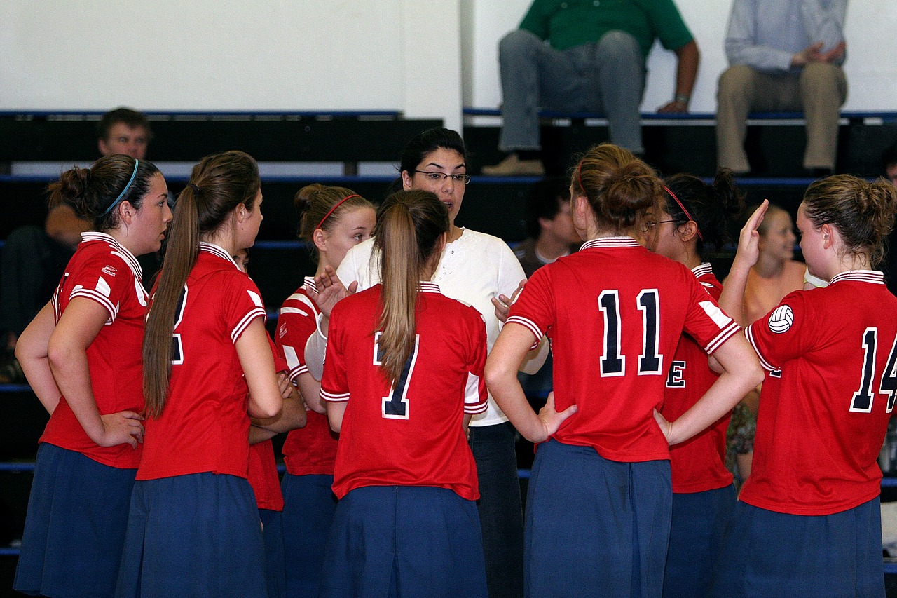 Young volleyball team huddled with coach in the middle.