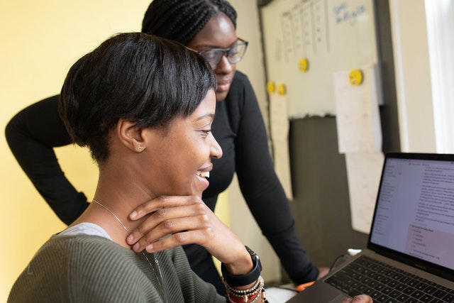 Women working in office looking at computer together.